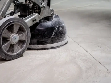 Průmyslová bruska brousí betonovou podlahu.