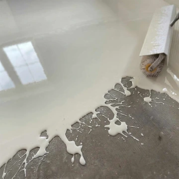 Váleček nanášející bílý nátěr na šedou podlahu.