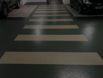 Přechod pro chodce v garáži mezi parkujícími auty.